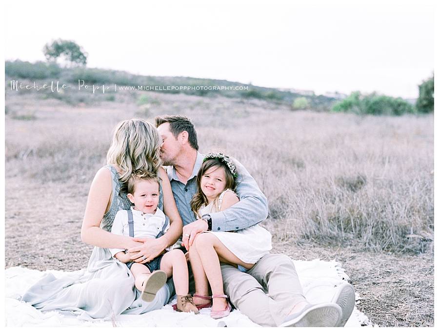 family of four snuggling close on a blanket