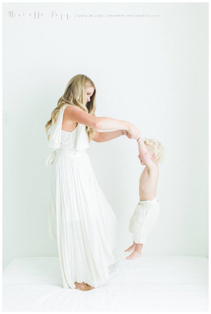 mom lifting up little boy by hands