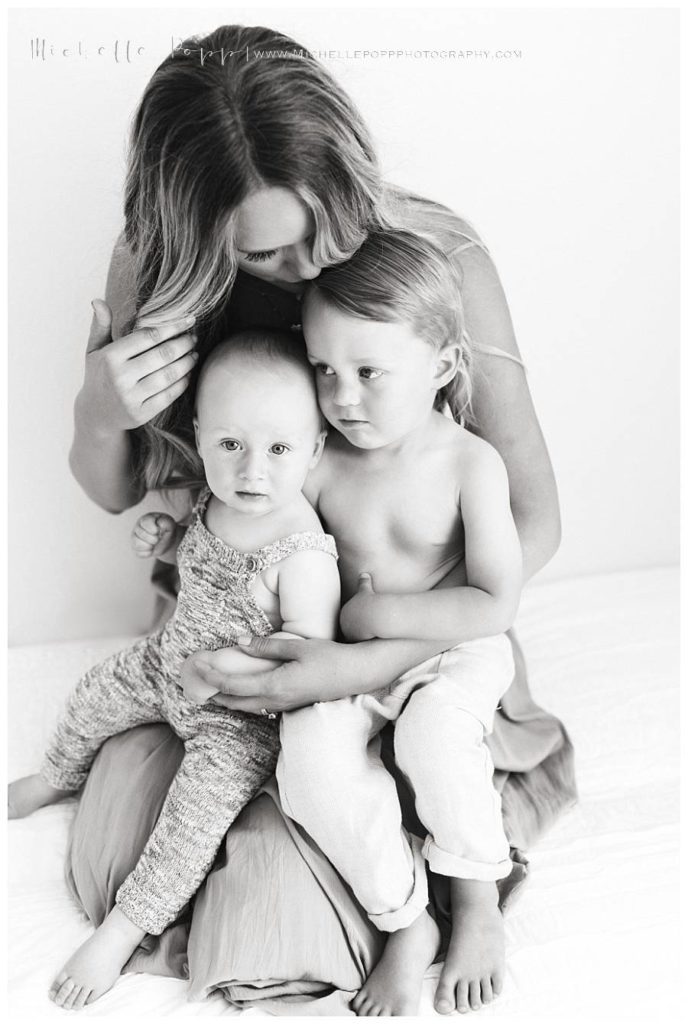 black and white of mom holding two boys in lap