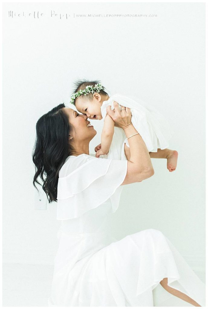 mom lifting baby up and smiling