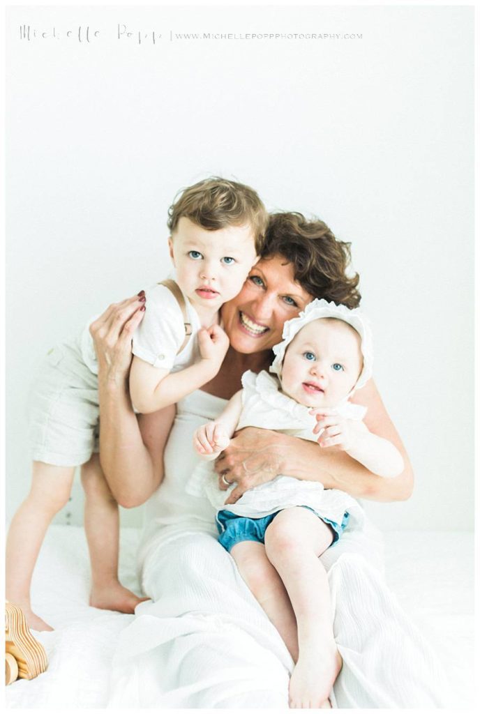 grandma holding two kids in arms smiling