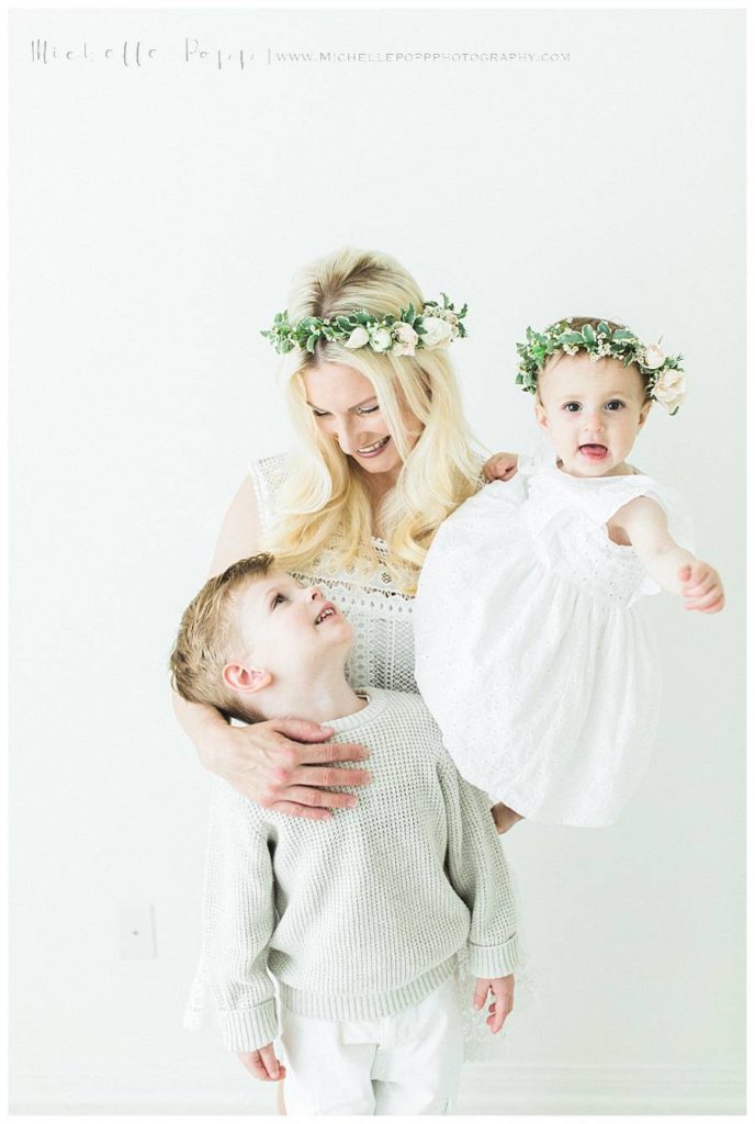 mom holding daughter while son looks up at her