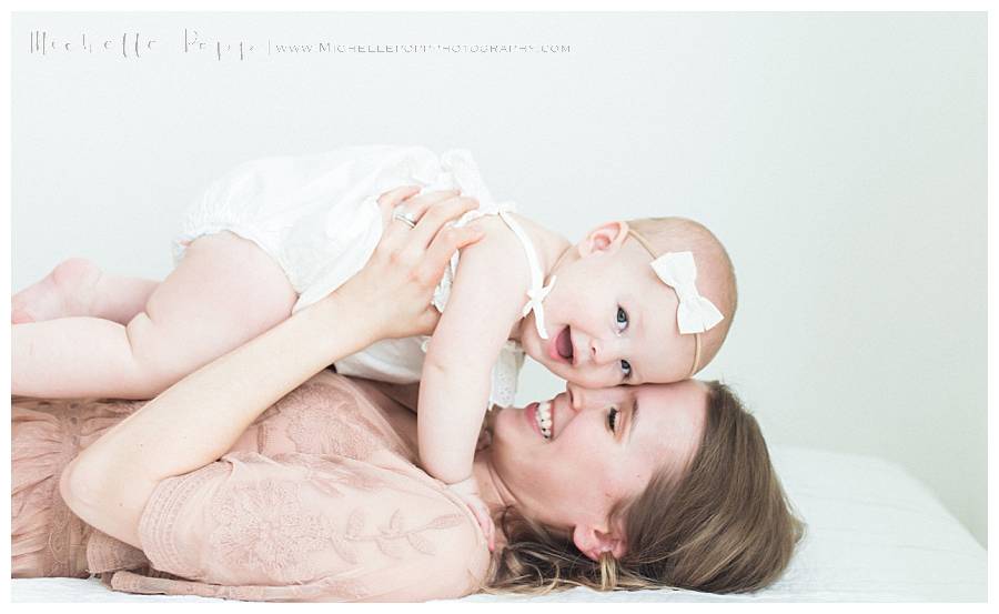 mom laying on back while smiling at baby