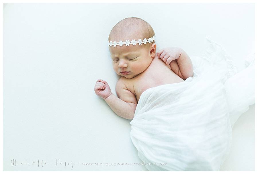 newborn baby girl in flower headband asleep
