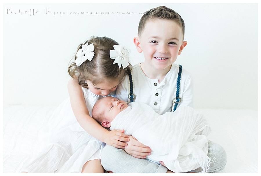 boy and girl holding baby in arms