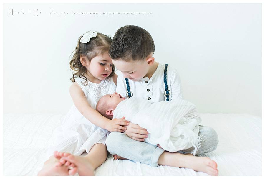 newborn baby in little boys arms yawning