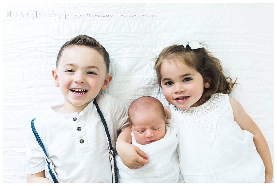 three children lying on bed smiling