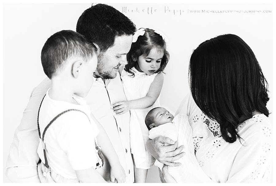 black and white of family looking down at newborn baby