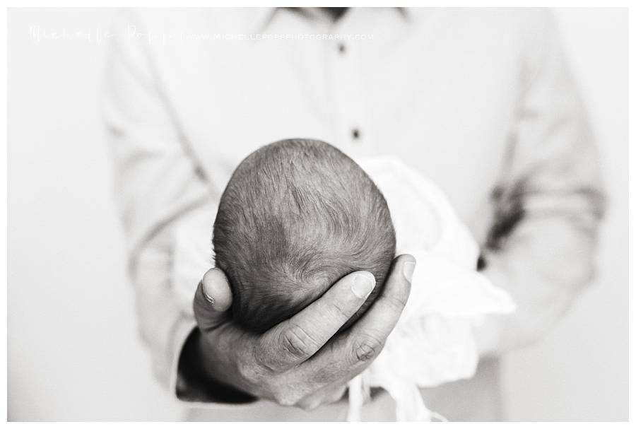 newborn baby head in dads hands close up