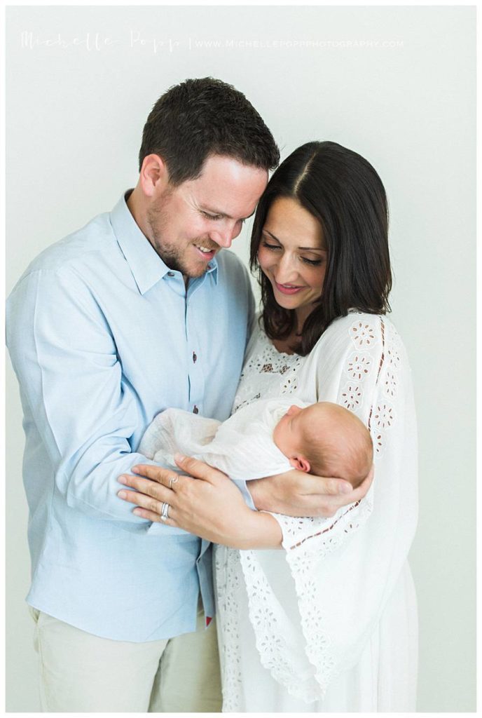 dad and mom holding new baby and smiling