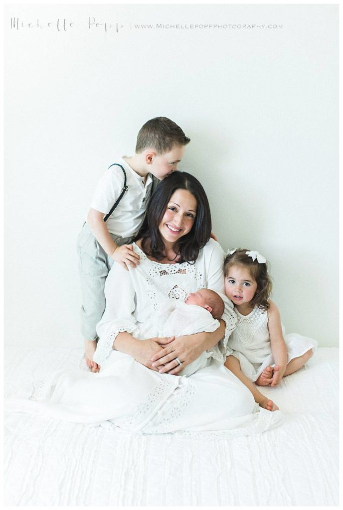 mom holding new baby as son and daughter sit next to her