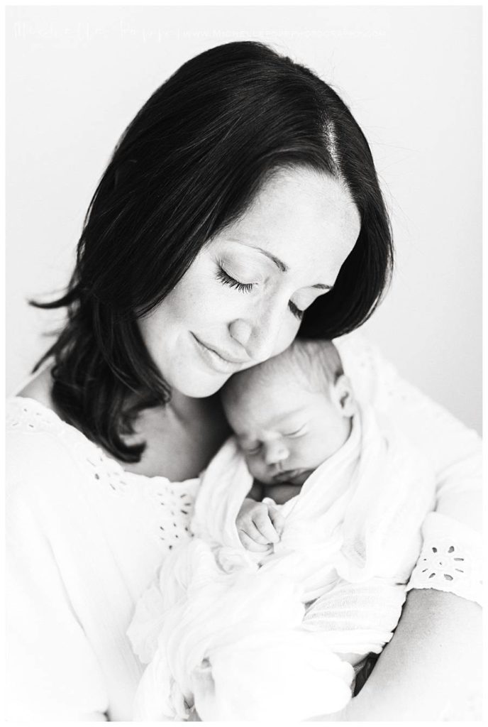 mom holding baby with eyes closed smiling