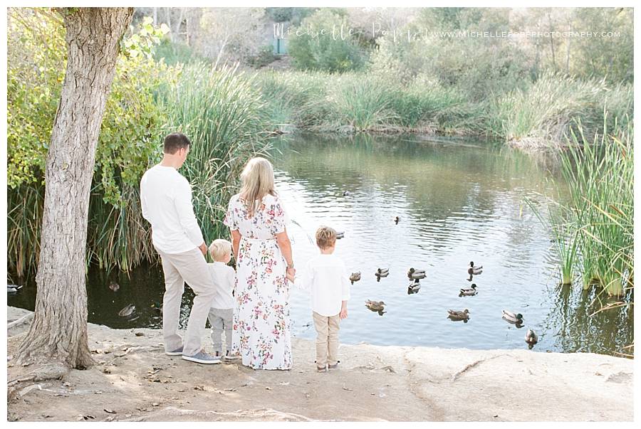 family of four looking at lake with ducks