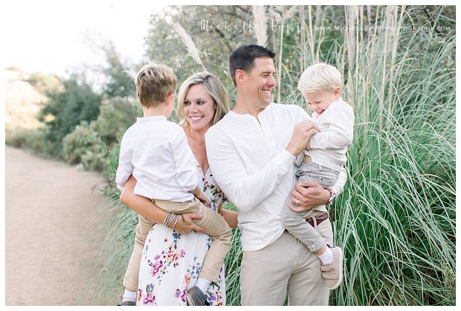 mom and dad holding toddler boys laughing