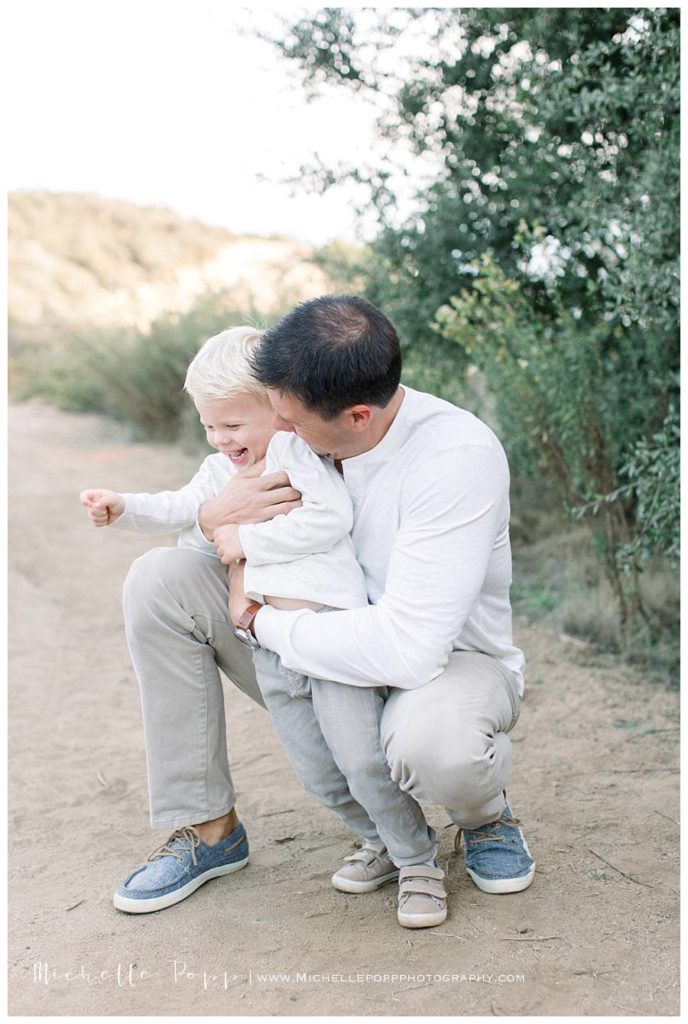 dad holding toddler boy and laughing