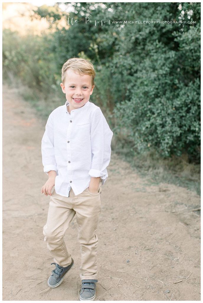 toddler boy in white shirt tan pants smiling