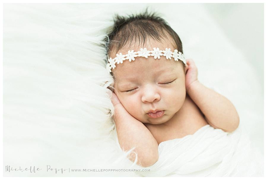 baby girl in white headband and white swaddle