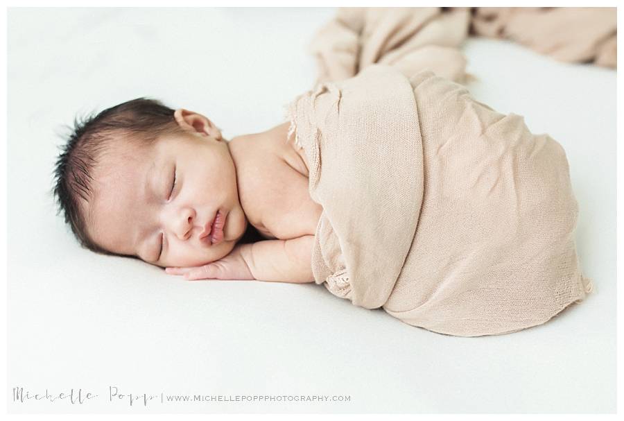 newborn girl wrapped in a brown swaddle