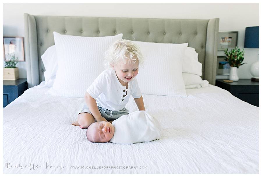 big brother on bed with newborn sister