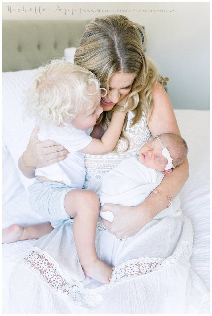 mom holding two kids on bed