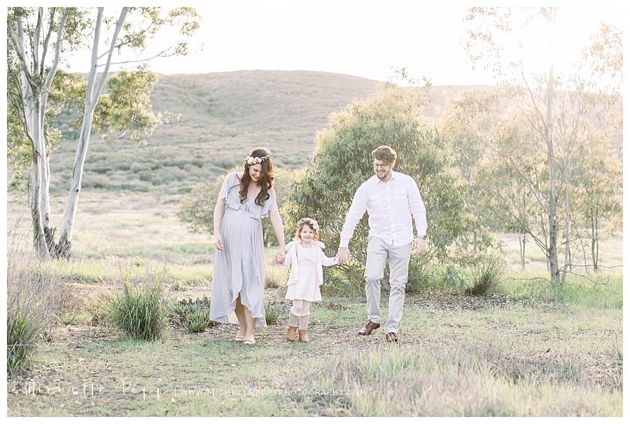 family of three walking in field