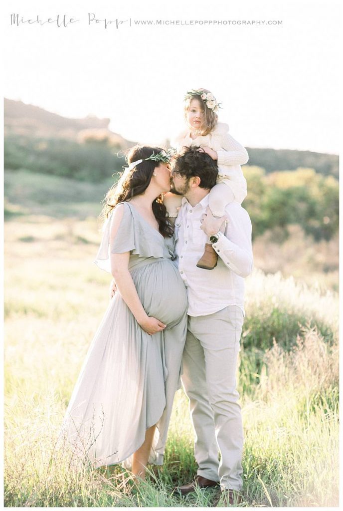 dad holding daughter on shoulder while kissing mom