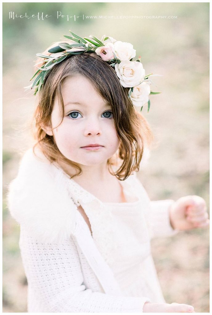 little girl in flower crown looking at camera