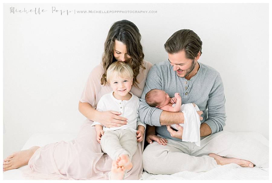 family of four sitting on bed