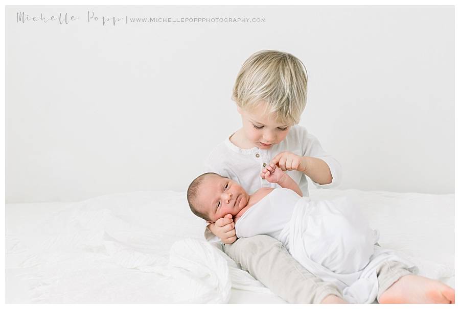 boy holding baby brother on bed