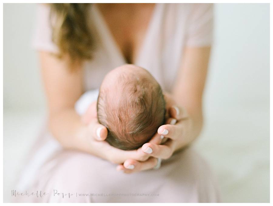 moms hands holding new baby