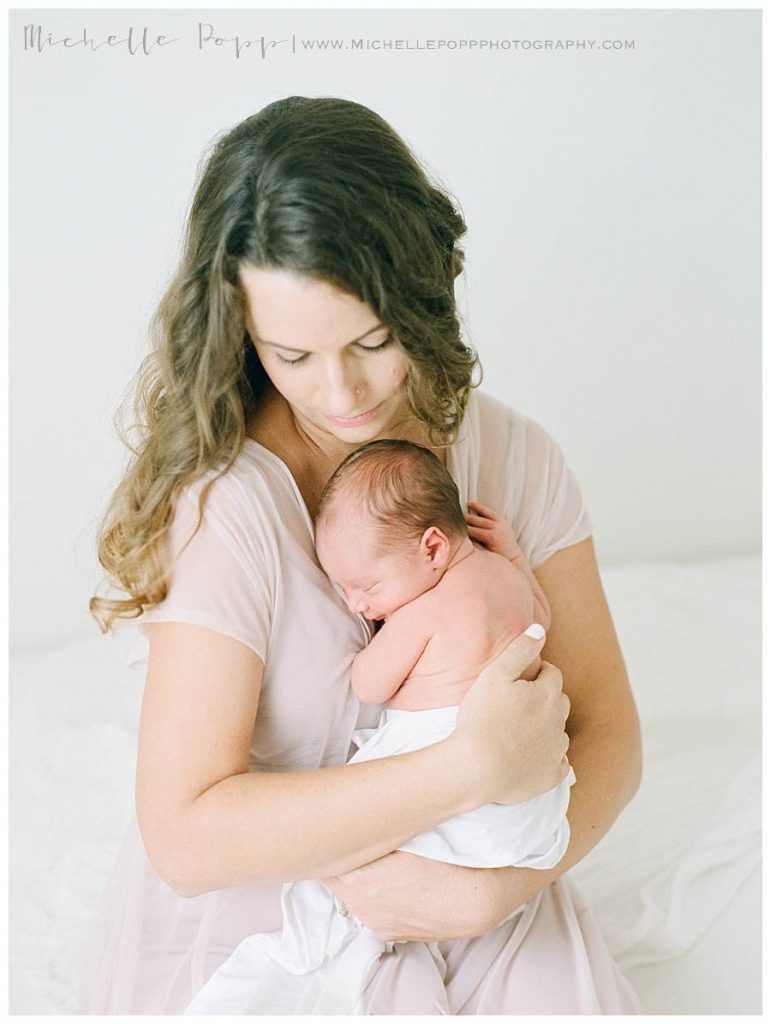 mom snuggling newborn baby on chest