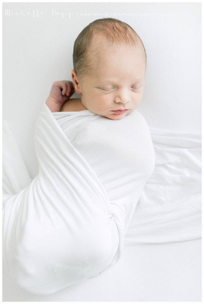 newborn baby boy in white swaddle