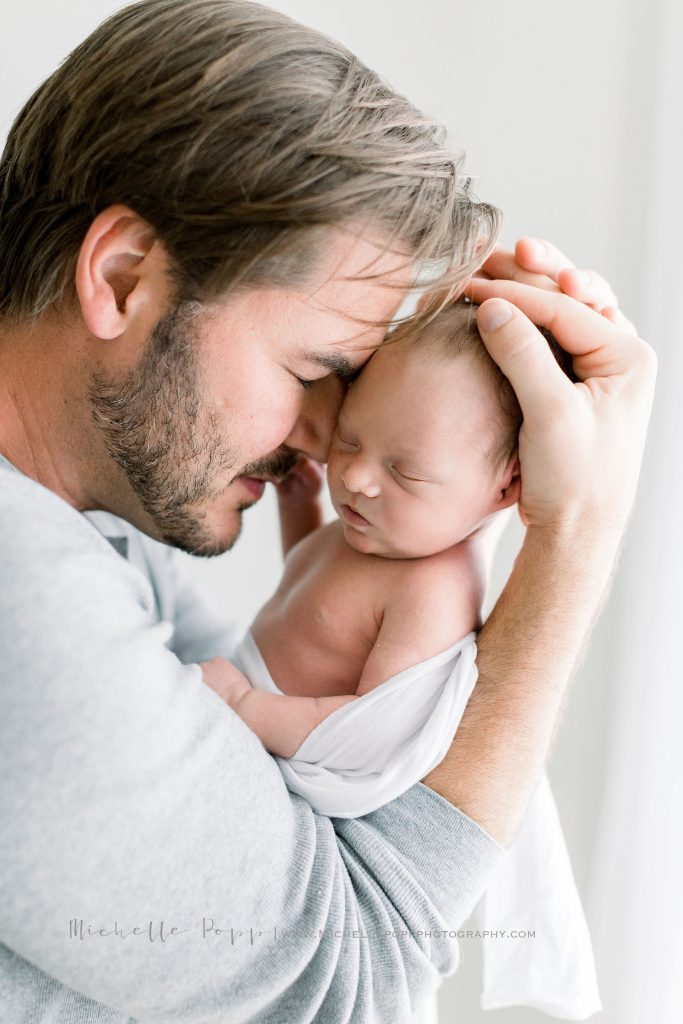 dad snuggling newborn baby boy