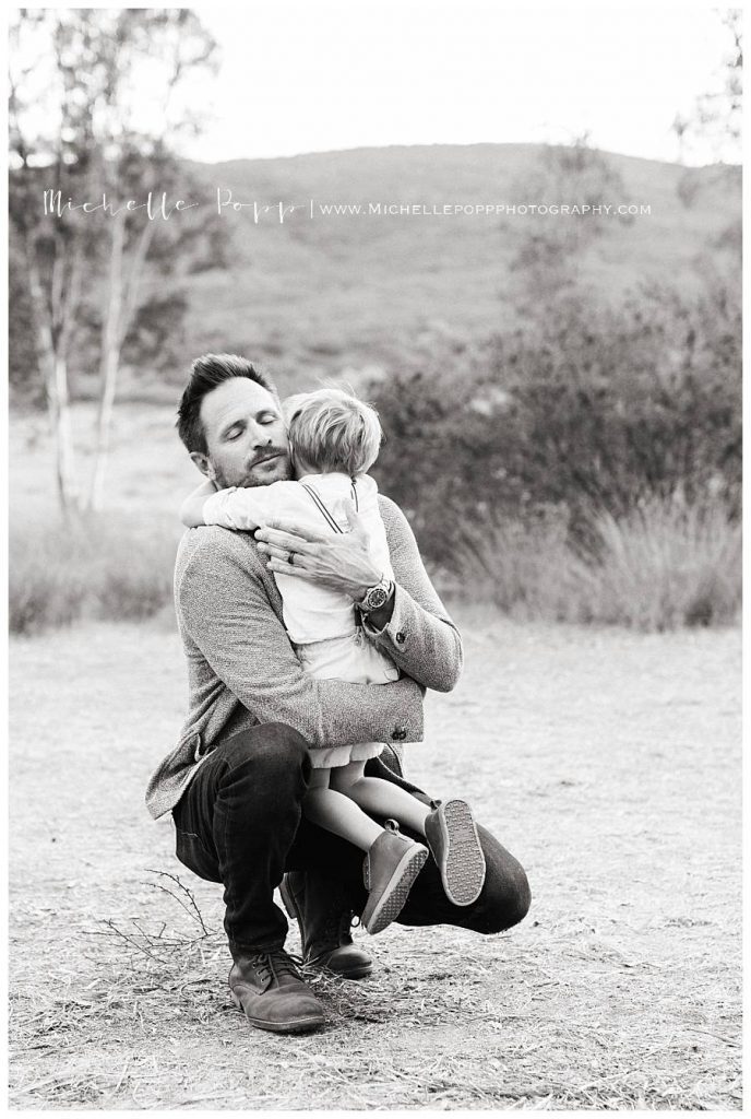 black and white dad hugging son in field