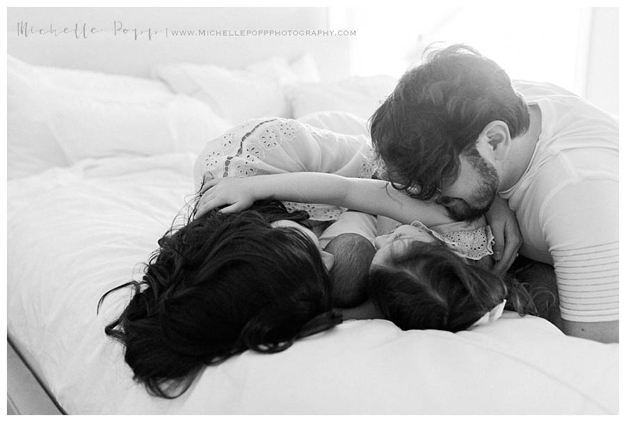 family of four snuggling on bed