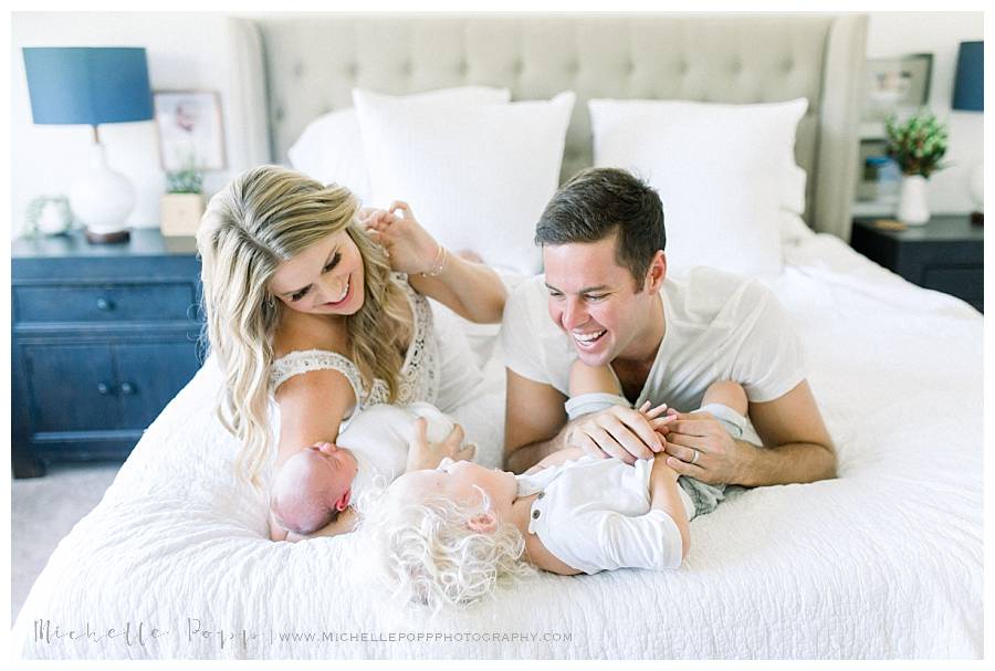 family of four laughing on bed