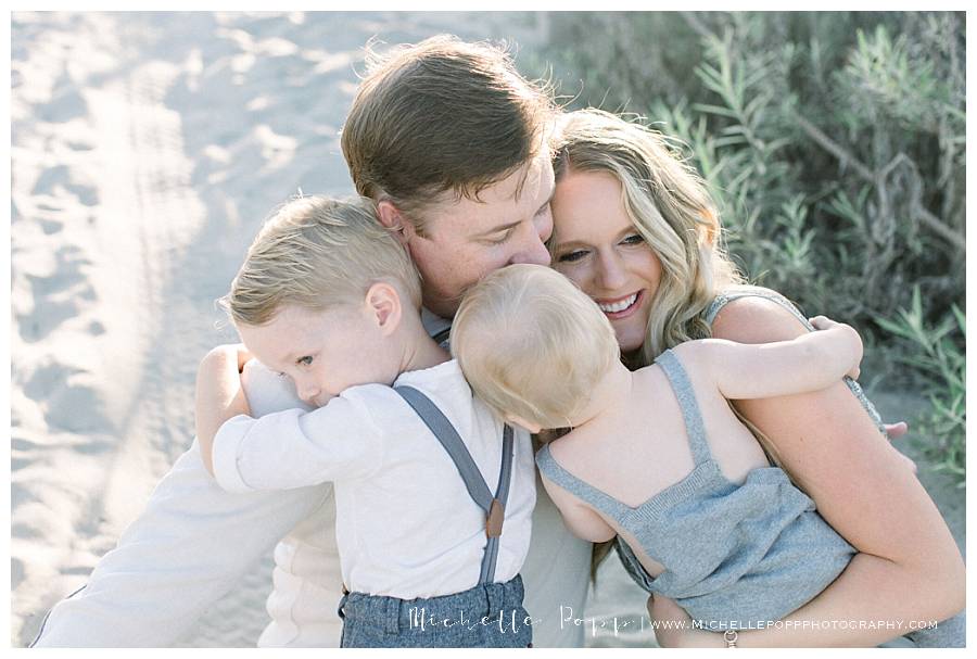 mom and dad hugging two sons