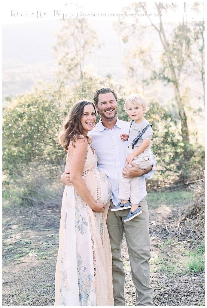 family smiling at camera in field in North County San Diego 
