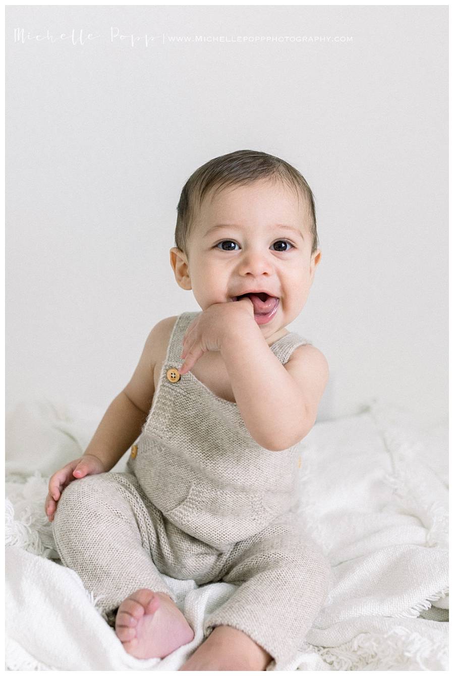 6 month old baby smiling with thumb in his mouth