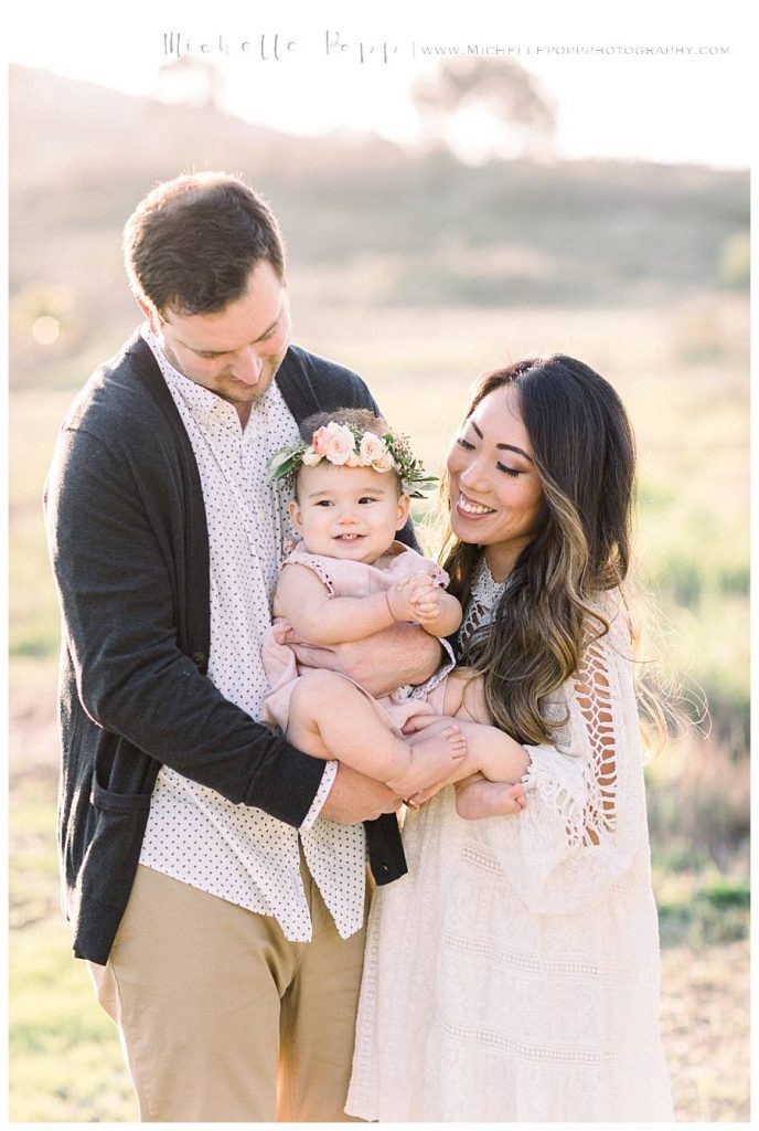 mom and dad smiling at baby girl 