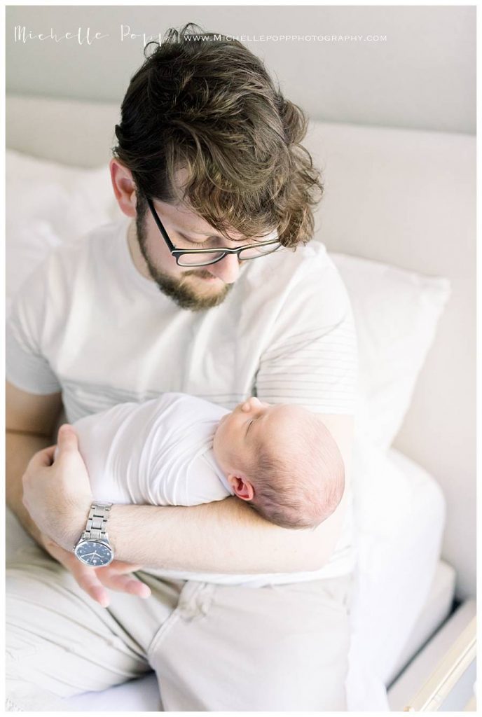 dad with glasses holding newborn