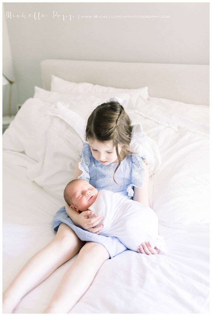 big sister holding newborn baby brother
