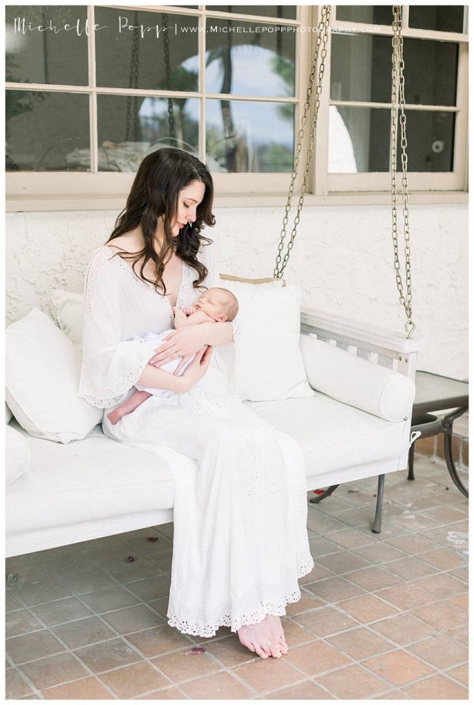 mom sitting on porch holding newborn baby