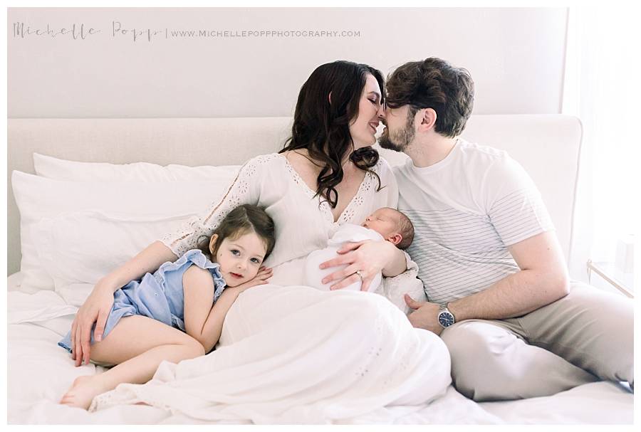 family of four sitting on bed smiling