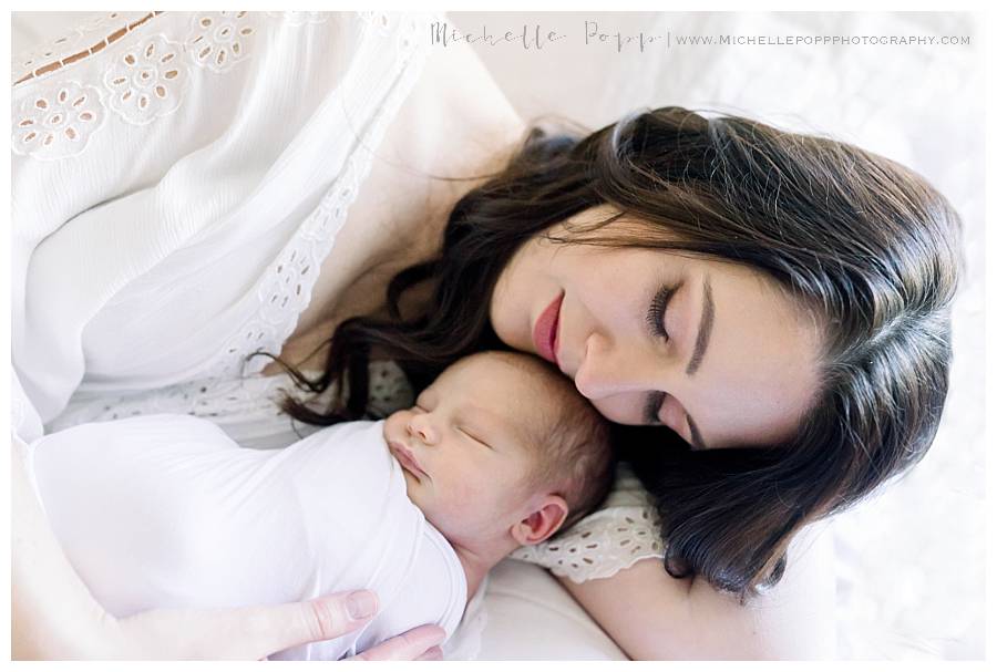 mom with eyes closed on bed with baby