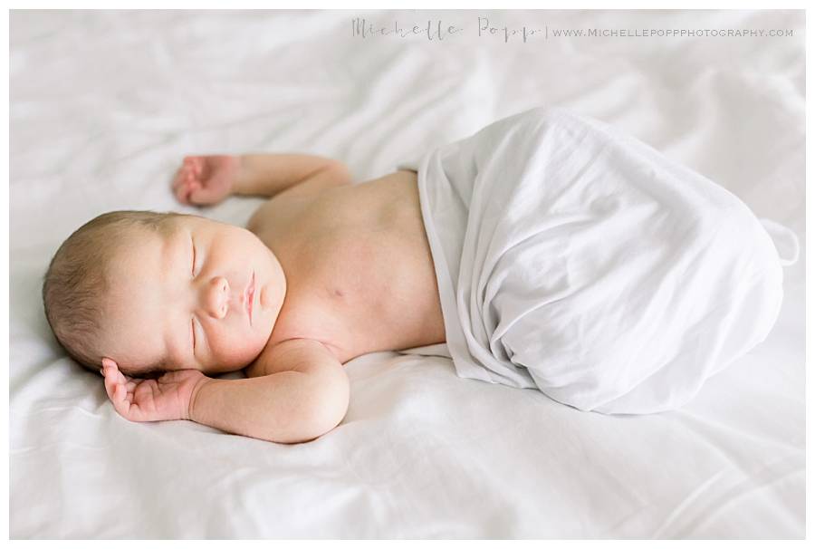 newborn baby on bed in swaddle