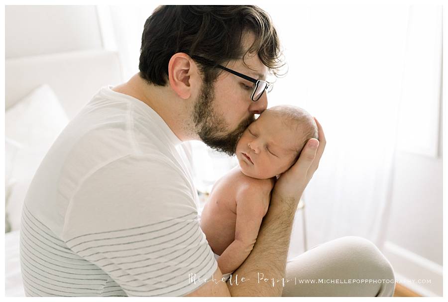 dad kissing newborn baby's head