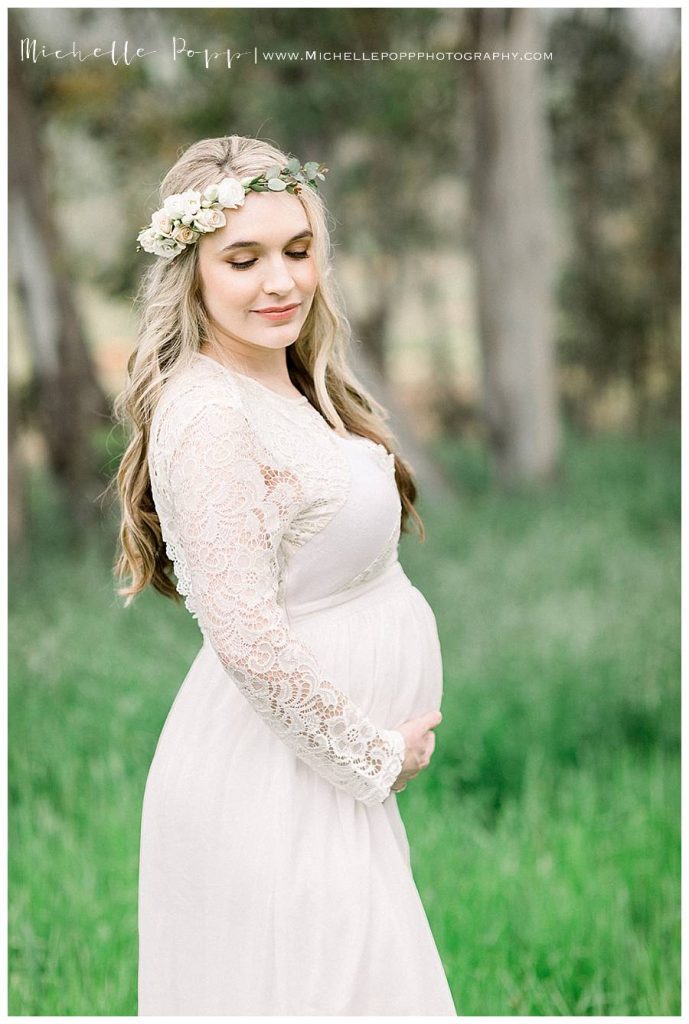 pregnant mother in green field in a white dress