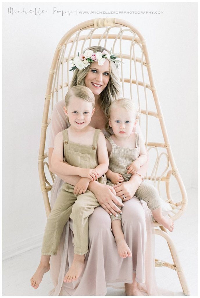 mom holding two boys on a chair