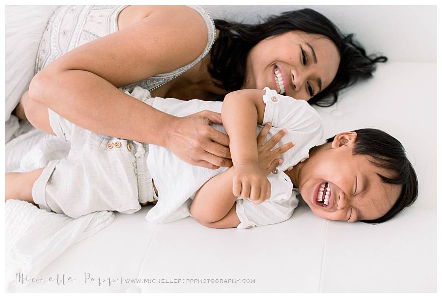 mom tickling son on bed